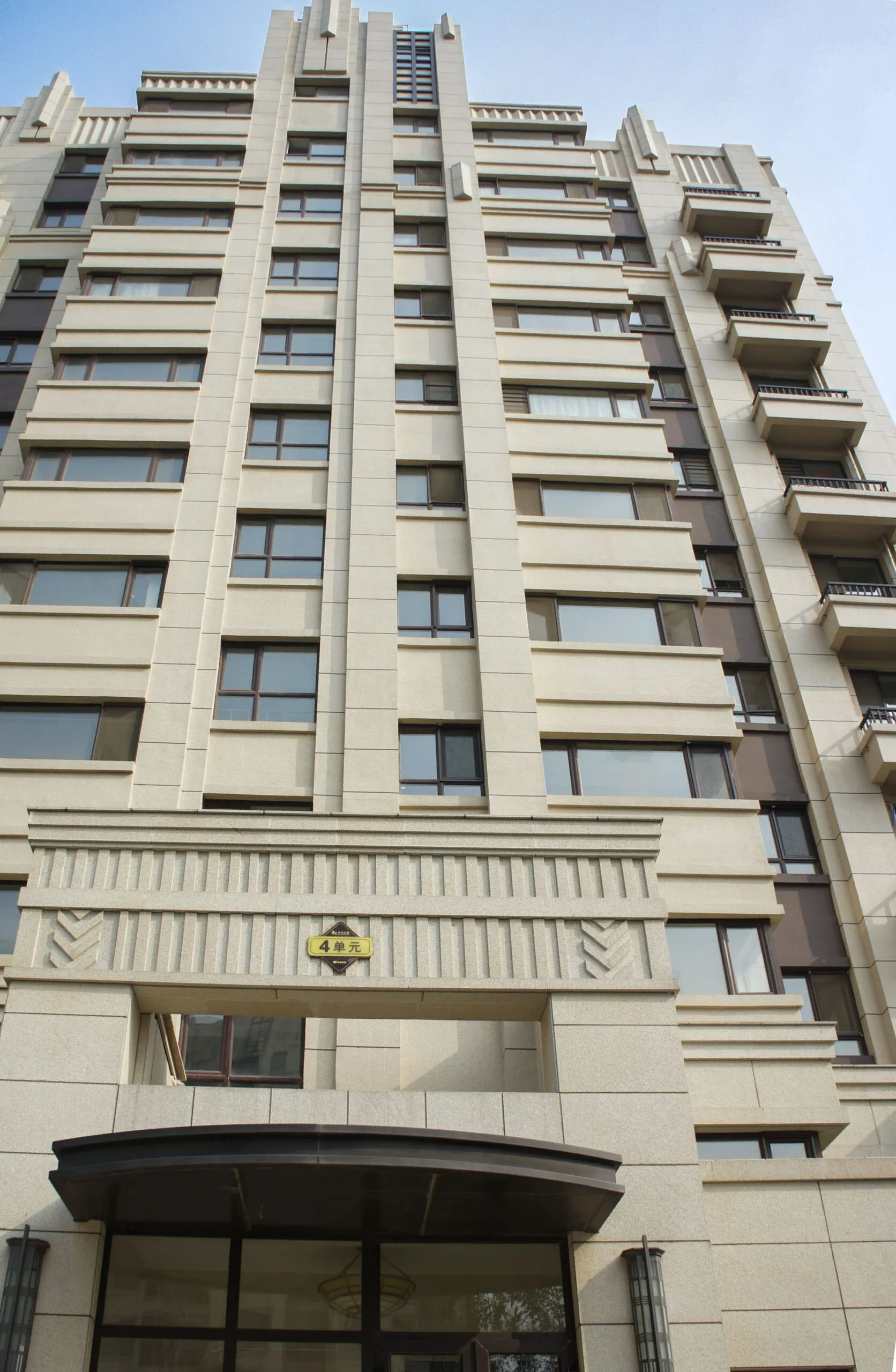 A modern apartment building with many windows and balconies stands tall against a clear sky.